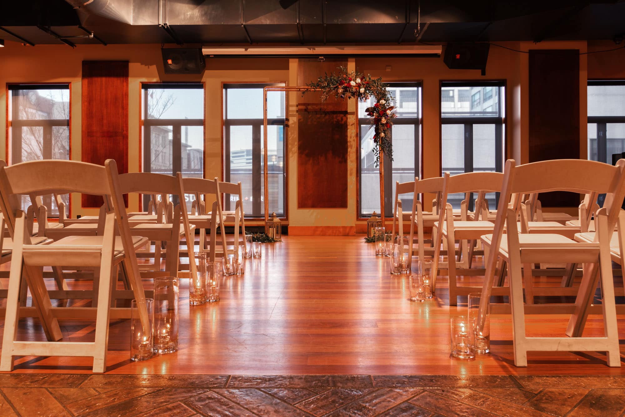 Saltlik's wedding event space setup with seating for guests, downtown Calgary visible through the windows at the end of the room behind the ceremony space.