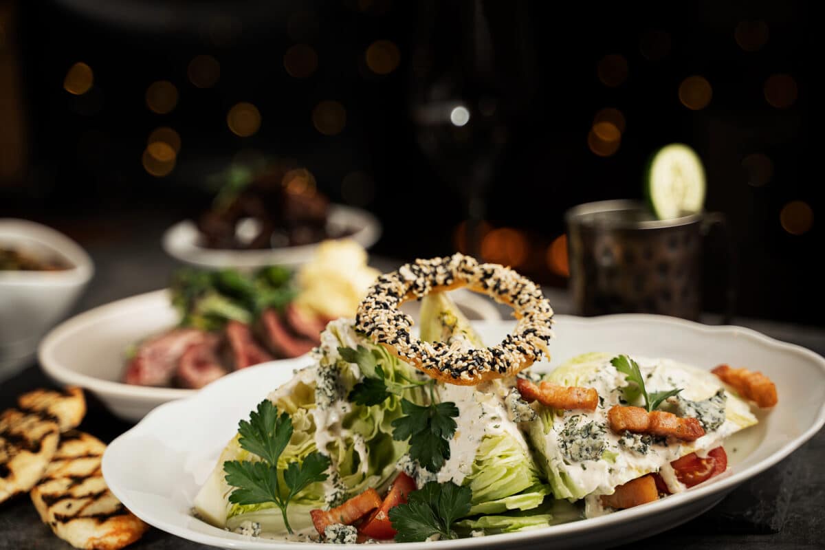 An intricate saltlik salad, with various greens, croutons, and a circular breadstick