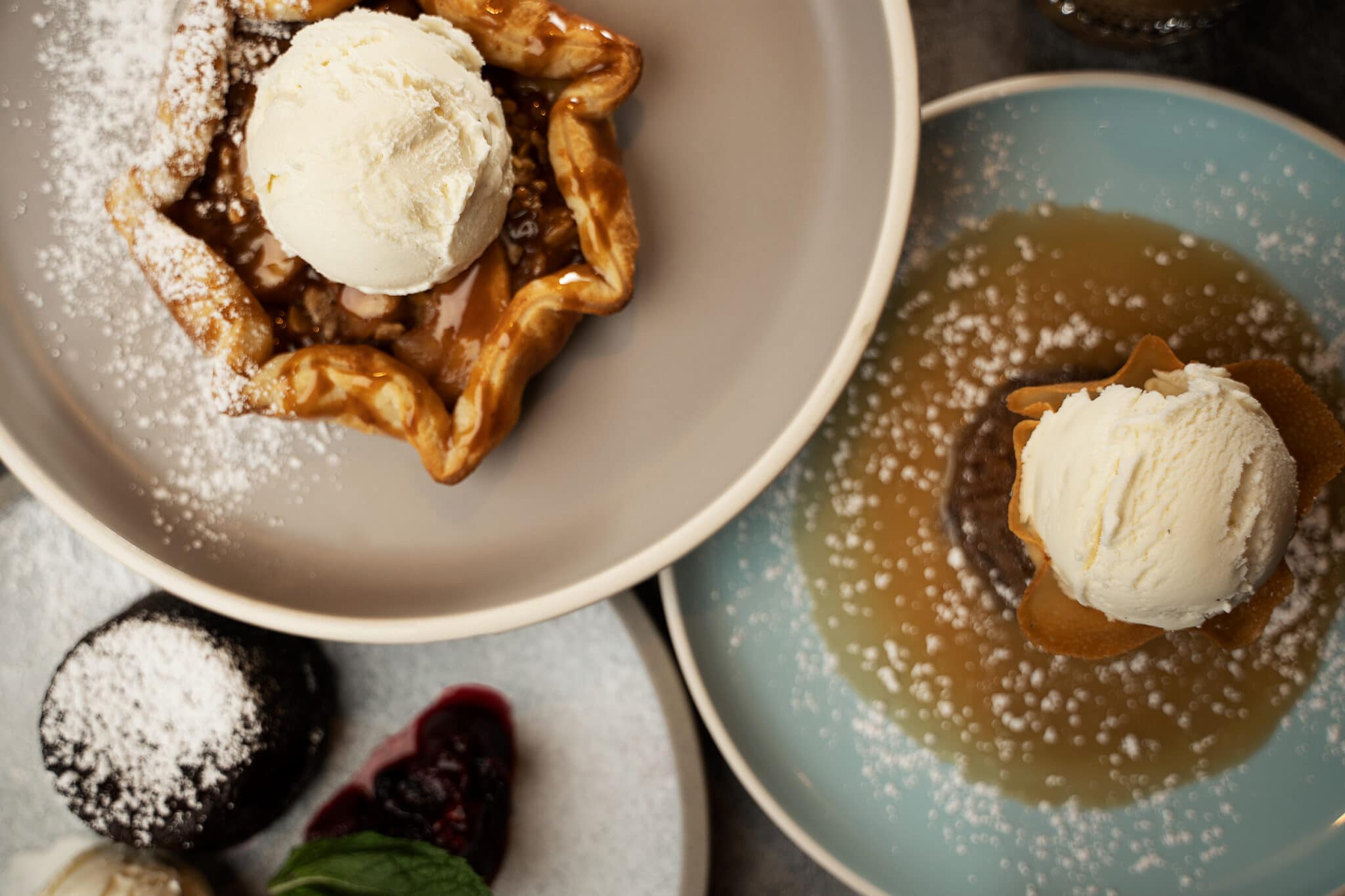 Three of Saltlik's desserts on round plates, pictured from above.