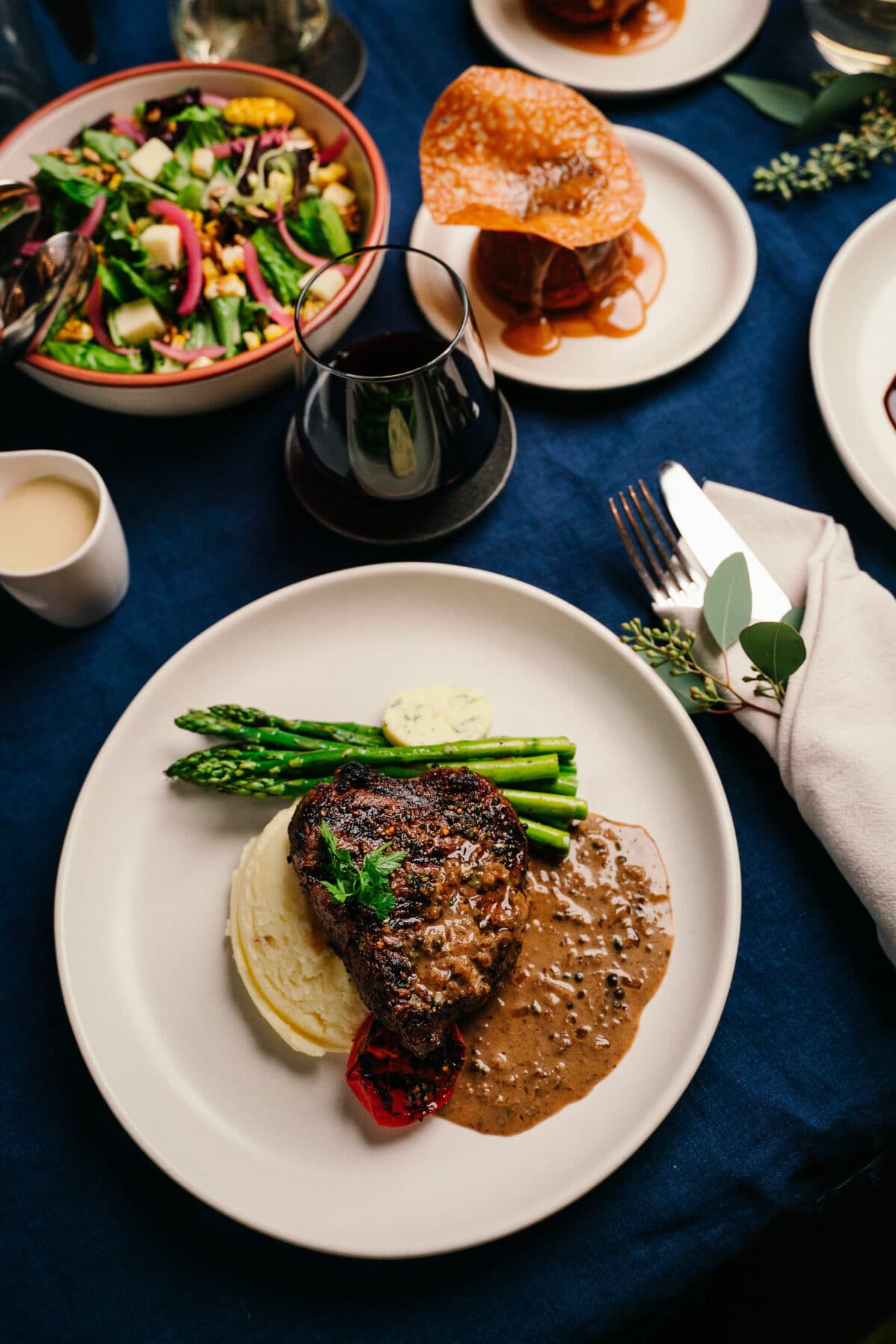 A steam main course setting with a salad, pudding and red wine.