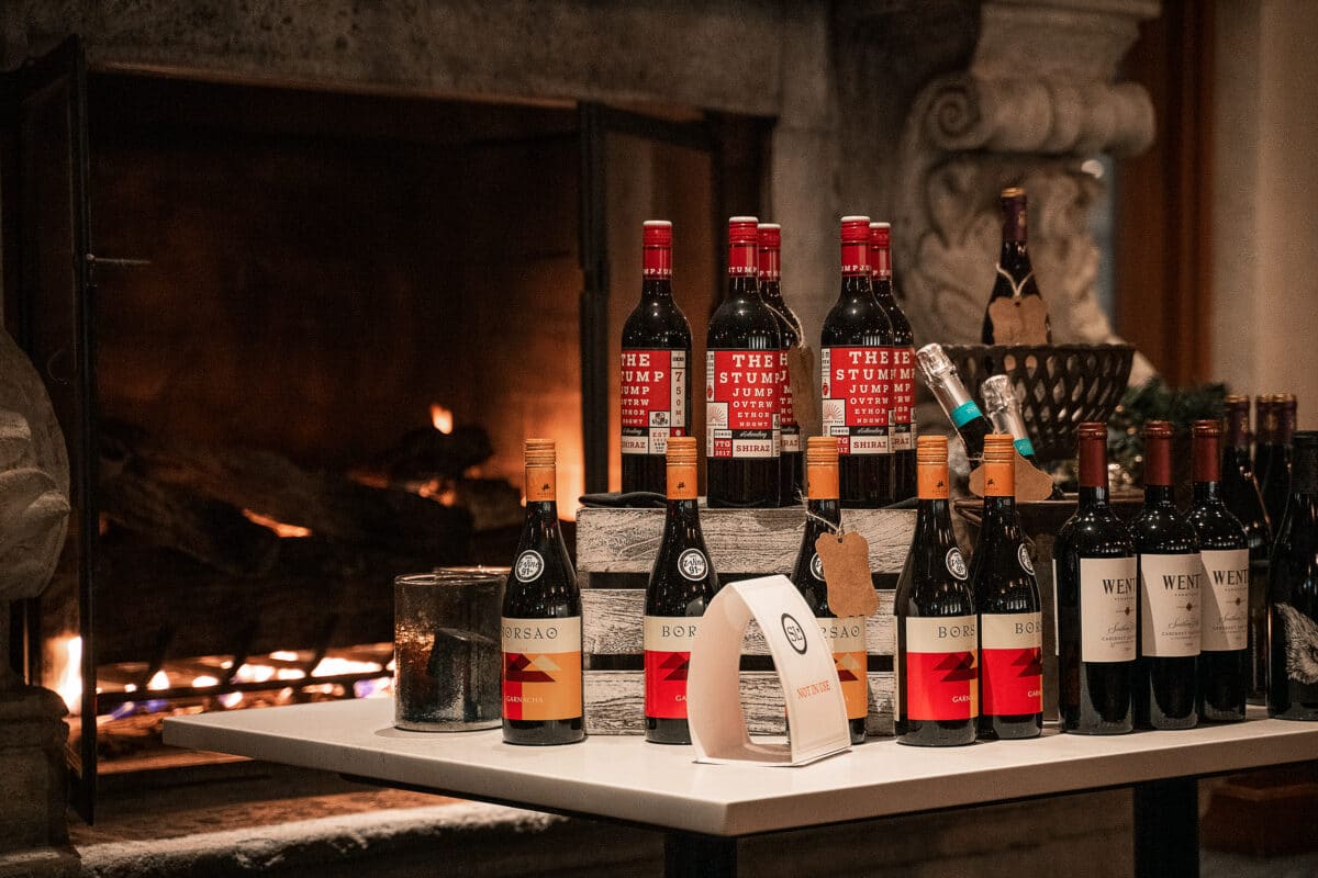 A selection of wines and champagnes on a white table in front of a large fire place