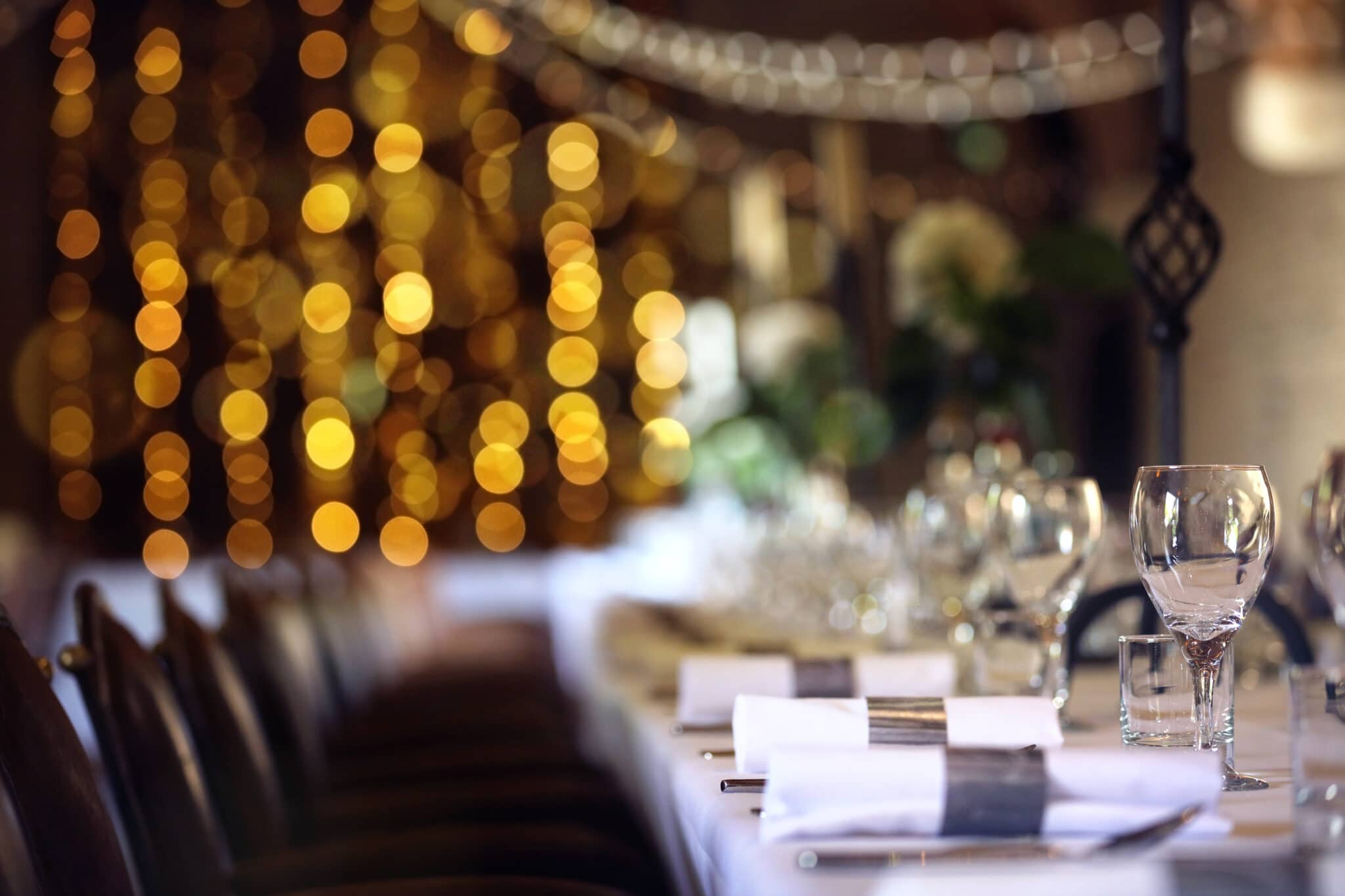 Formal wedding place setting on long table background focus on wine glass