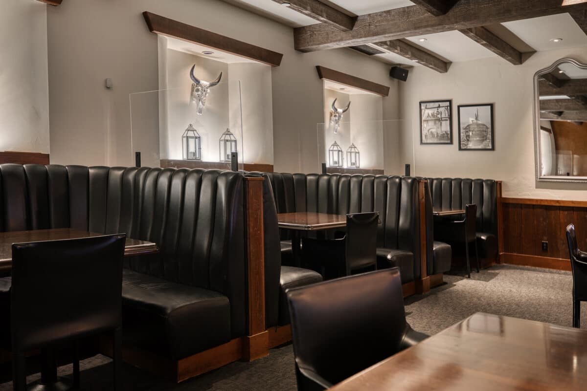 Three black eating booths in the Saltlik main dining room, western decor on the wall